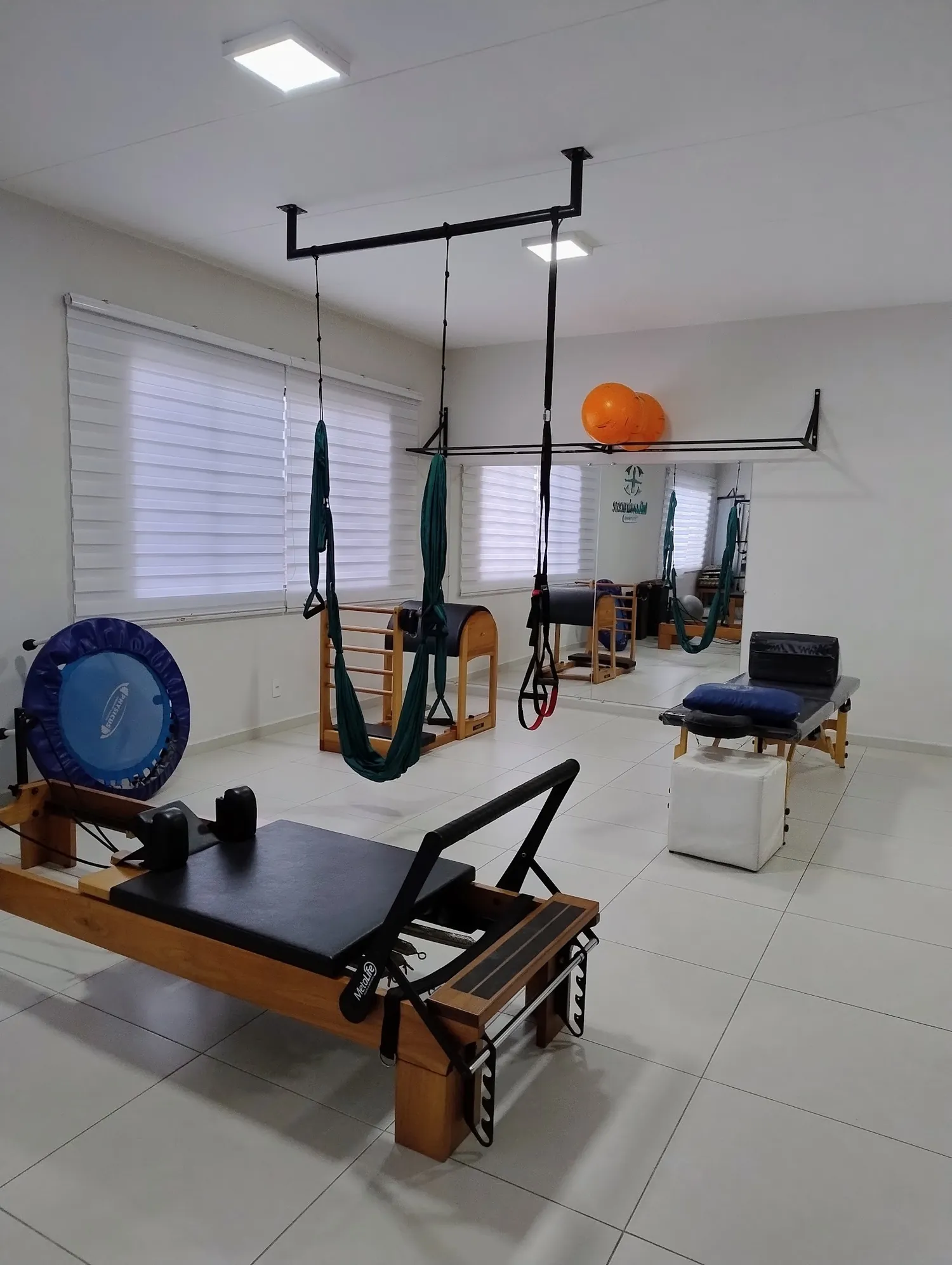 Sala de pilates terapêutico com aparelhos e janelas amplas