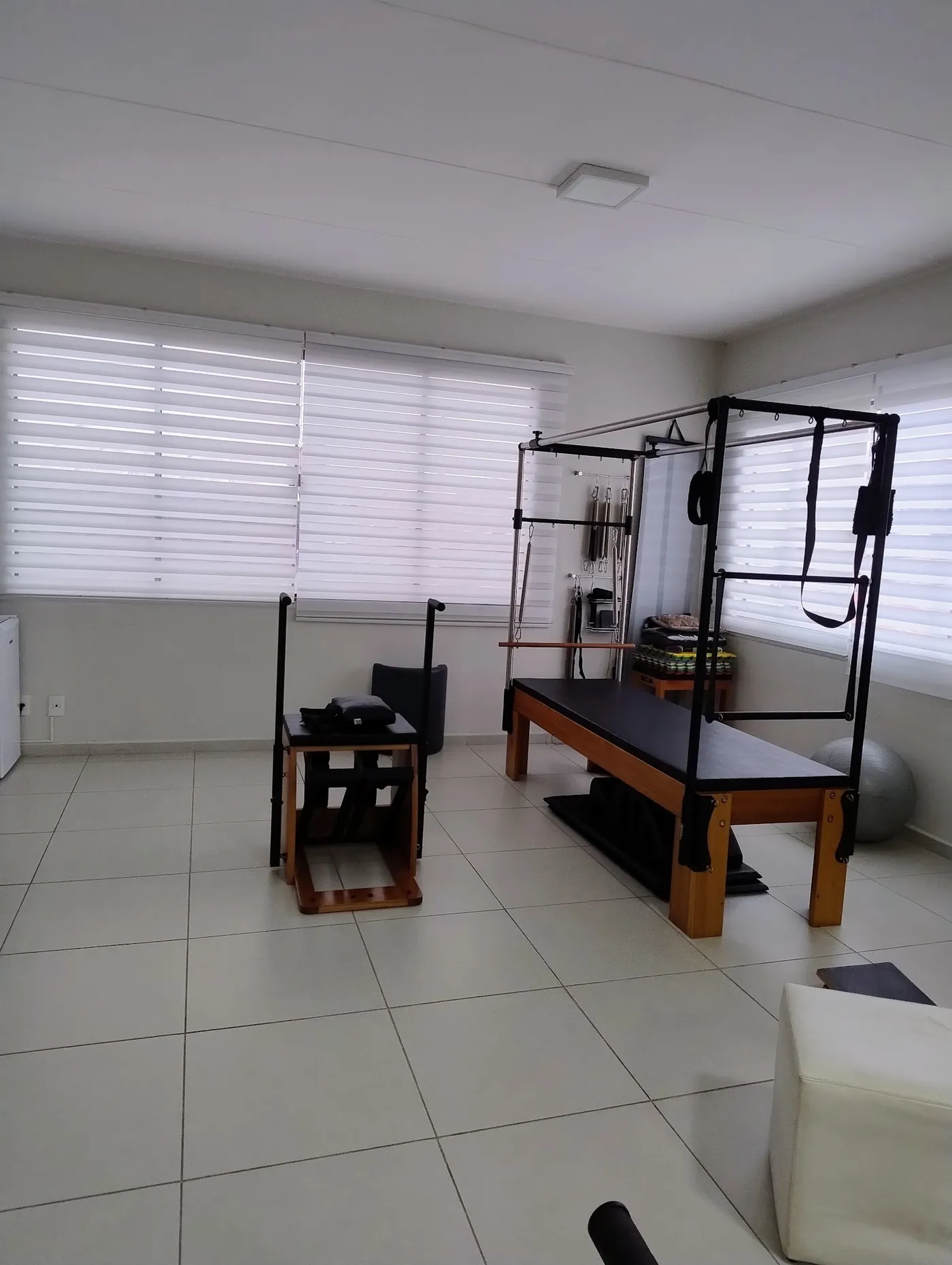 Sala com aparelho de pilates cadillac e janelas amplas