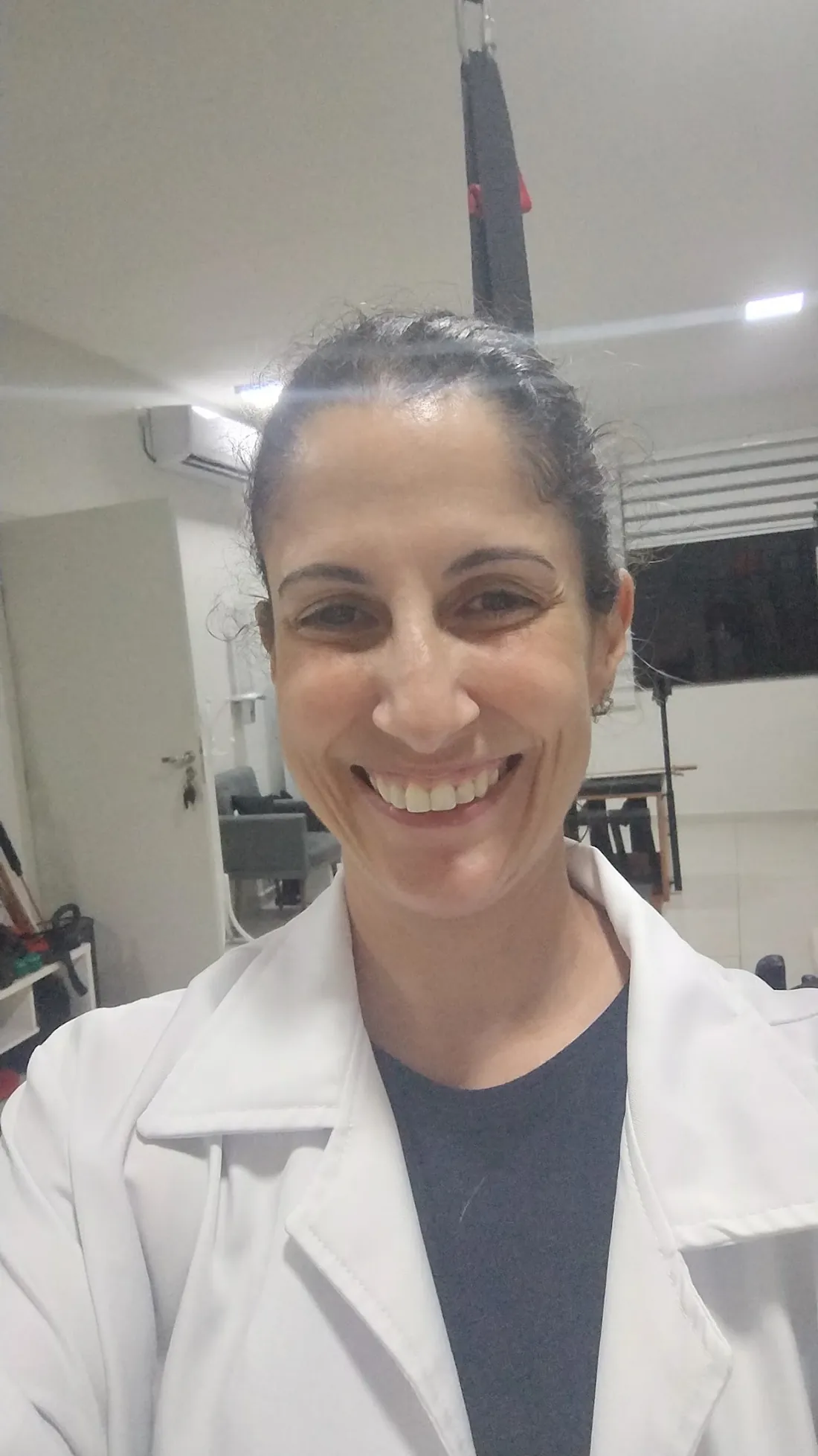 Fisioterapeuta Tatiana Abruceze de jaleco no espaço de atendimento